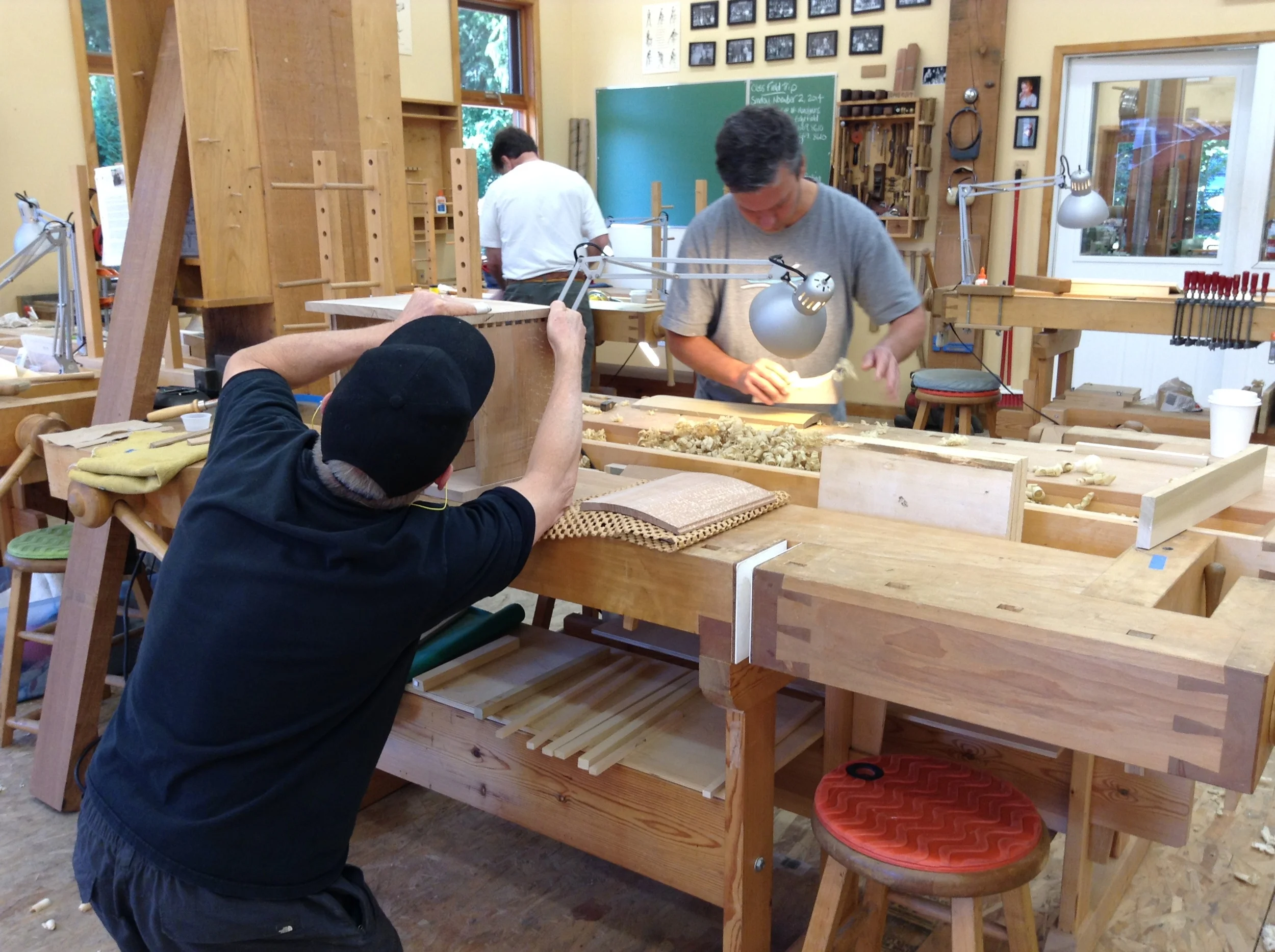 John fits the top of his cabinet; Mike planes his coopered door